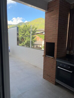 Zona de pati amb una barbacoa de maó i vista a un paisatge amb muntanyes.