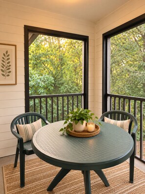 A round table with chairs and a potted plant on a balcony with a view of trees. - Classic City Clubhouse w/ Community Pool (Athens)