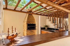 A kitchen with a brick oven, wooden beams, a ship model, and a sink. - New Listing (Arraial d'Ajuda)