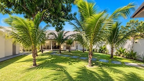 A courtyard with palm trees, a covered seating area, and a building with a tiled roof. - New Listing (Arraial d'Ajuda)
