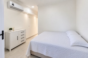 A bedroom with a bed, a dresser, and an air conditioning unit. - New Listing (Arraial d'Ajuda)