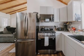 A compact kitchen with a stainless steel refrigerator, a gas stove, and a microwave. - Wonderful 2-bedroom cabin in Big Bear for a relaxing getaway (Big Bear)