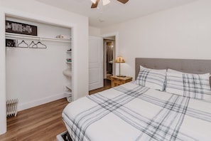 Une chambre à coucher comprenant un lit, une table de chevet, une lampe, une armoire et un radiateur.