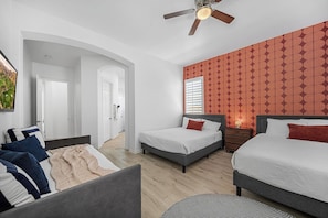 A modern bedroom with two beds, a ceiling fan, and a patterned wall. - All-Inclusive Retreat: Pool | HotTub | Golf | Games (Indio)