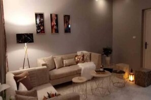 A living room with a sofa, a coffee table, and a floor lamp. - Apartment "NAFAS"❤️ de la résidence Maisons Maktoub Djerba ❤️ (Djerba)