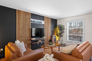 Ein modernes Wohnzimmer mit einer Couch, einem Couchtisch und einem Fernseher.