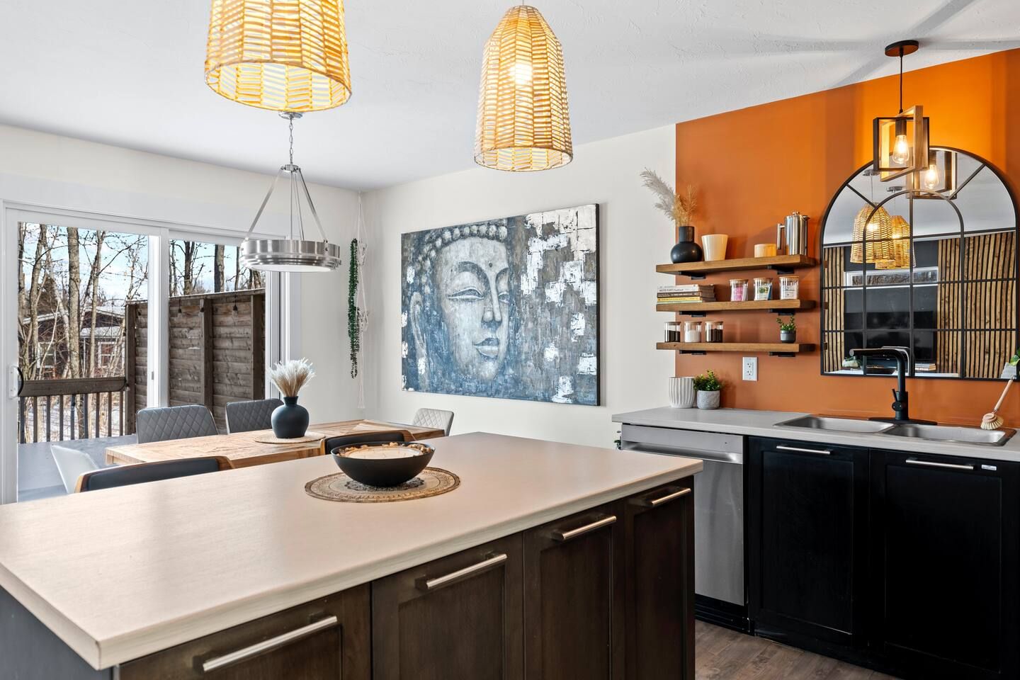 Una cucina moderna con isola centrale, illuminazione a sospensione e un grande dipinto di Buddha.