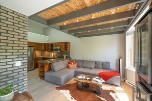 A modern living space with a kitchen, a sofa, a coffee table, and a TV. - Ski-in ski-out condo with mountain views, balcony, wifi, full kitchen. (Mountain Village)