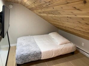 A small, single-bed room with a sloped ceiling and a wooden beam structure. - Ski-in ski-out condo with mountain views, balcony, wifi, full kitchen. (Mountain Village)