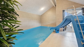 An indoor swimming pool with a blue slide, beige tiled walls, and a plant in the foreground. - VillaVilla 1007 - Henne Strand, Vestjylland (Henne)
