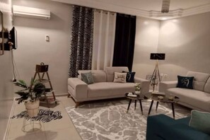 A living room with a sofa, coffee table, and a plant. - Apartment " Eshq " de la résidence Maisons Maktoub Djerba❤️ (Djerba)
