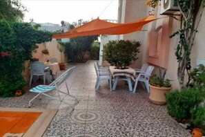 An outdoor patio area with a tiled floor, a table with chairs, and potted plants. - Apartment " Eshq " de la résidence Maisons Maktoub Djerba❤️ (Djerba)