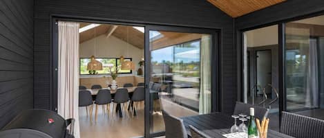 A modern interior with a dining area, a seating area with a table and chairs, and a view through large glass doors.