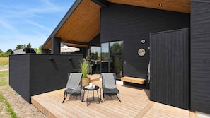 A modern outdoor seating area with two chairs and a table, a wooden deck, and a glass door leading to an interior space. - VillaVilla 1023 - Hasmark Strand, Fyn og øer (Otterup)