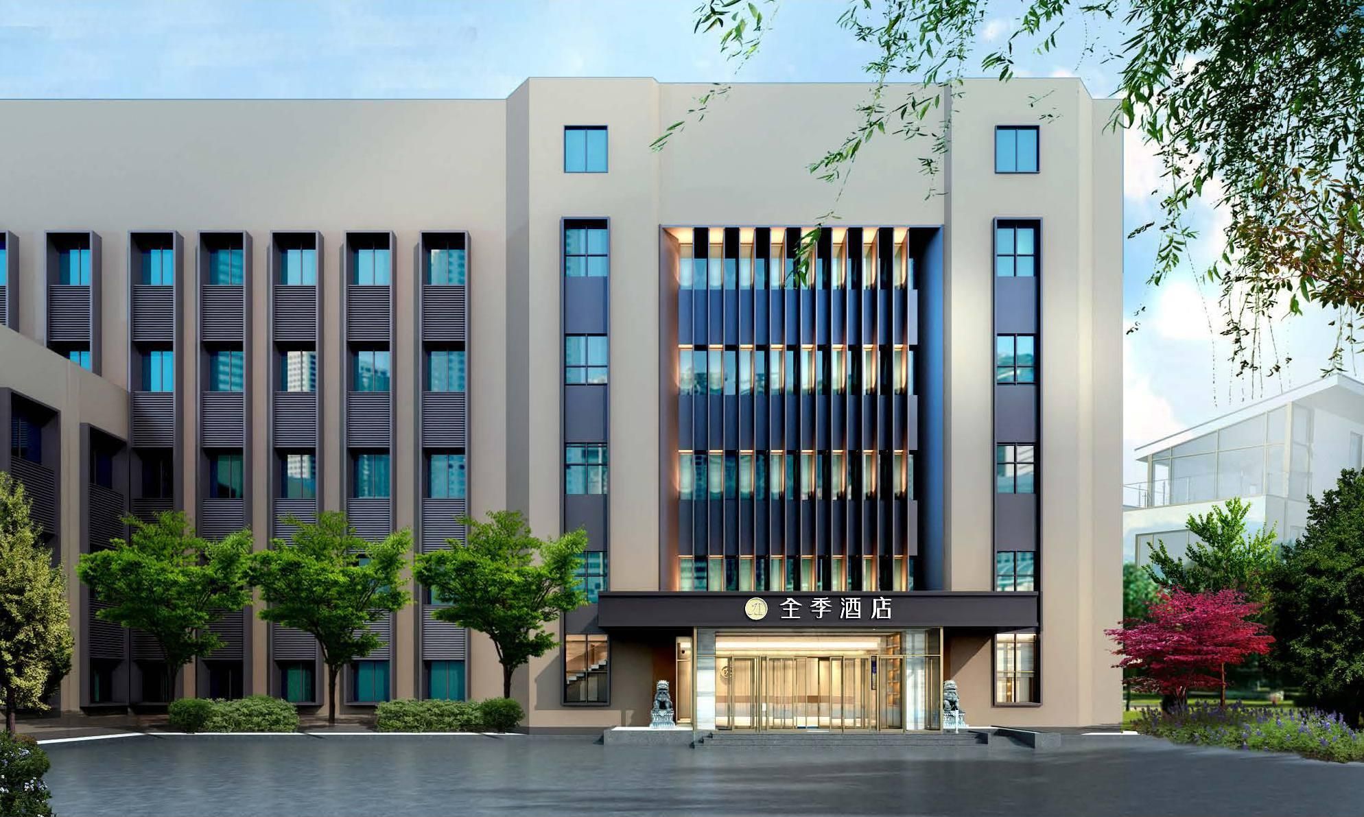 A modern hotel building with a central entrance, multiple floors, and a courtyard.