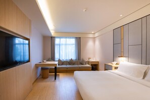 Een moderne hotelkamer met een bed, een bank, een bureau en een televisie.