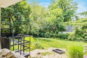 Ein Garten mit Holzterrasse, Steinmauer und verschiedenen Pflanzen.