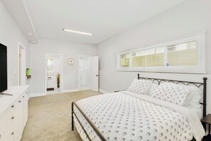 Ein Schlafzimmer mit Bett, Schminktisch und Fenster mit Jalousien.