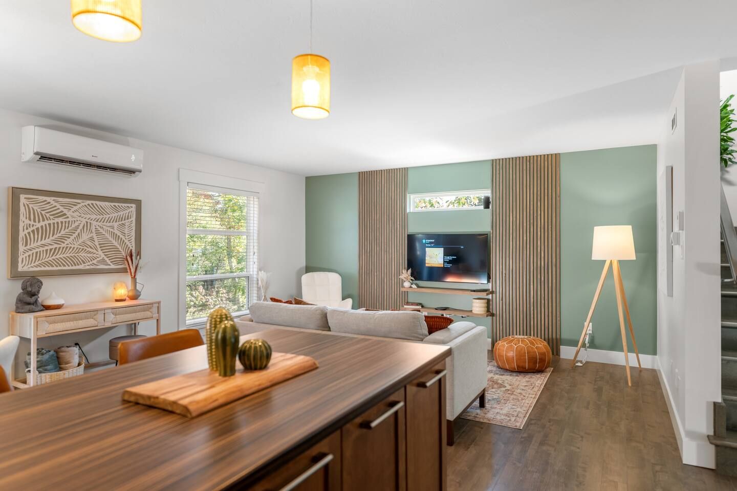 A modern living room with a wooden dining table, a sofa, a TV, and a lamp.
