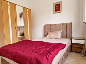 A bedroom with a bed, a wardrobe, a bedside table, and a framed picture on the wall. - The Nasser Retreat (Ariana)