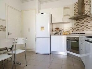 A modern kitchen with white cabinetry, a built-in oven, and a stainless steel range hood. - The Nasser Retreat (Ariana)