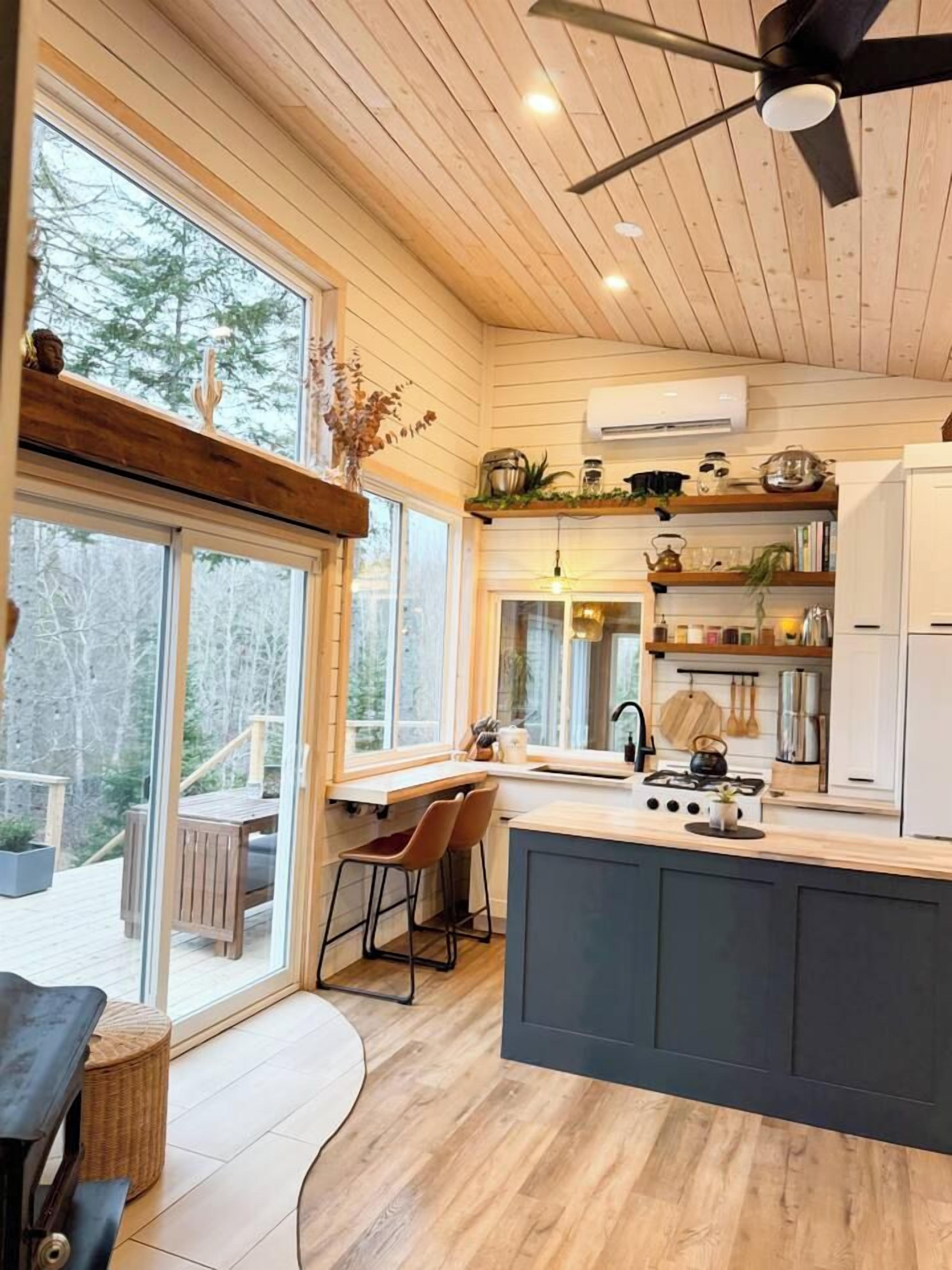 A modern kitchen with a central island, wooden cabinetry, and a built-in stove.