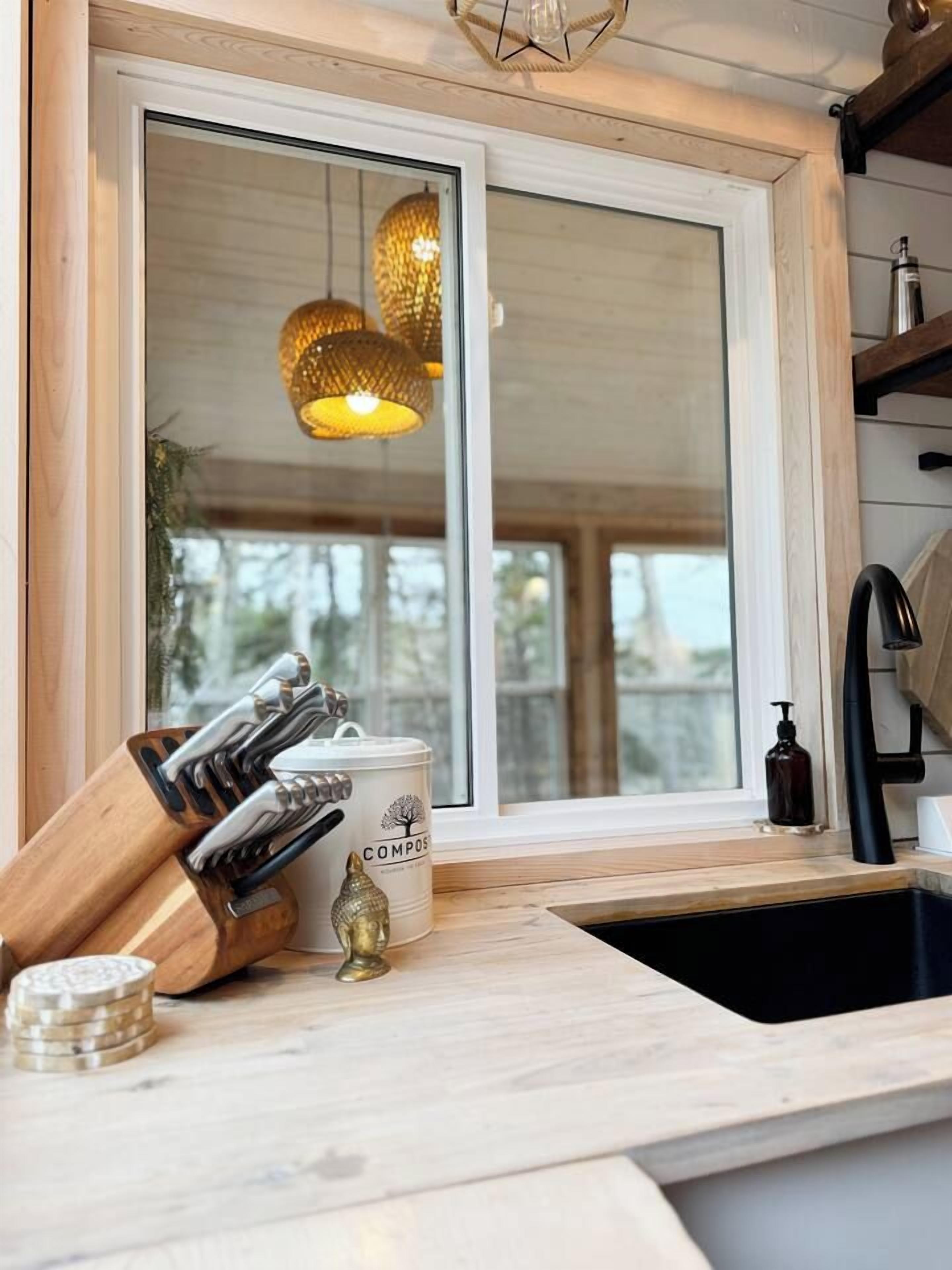 Una cocina con encimera de madera, un lavamanos y una ventana con vistas a árboles.
