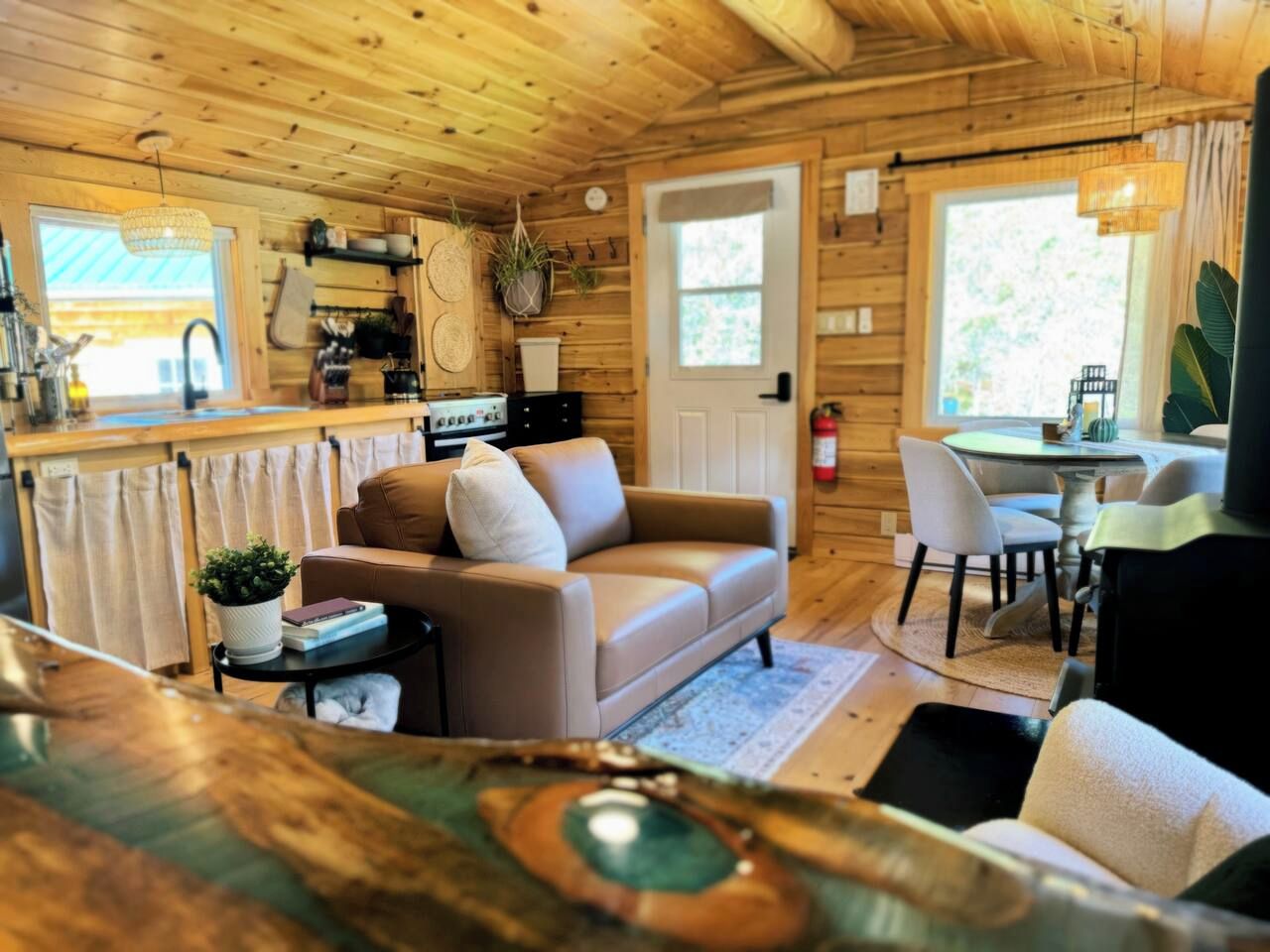 A cozy cabin interior with a sofa, dining table, and kitchen area.