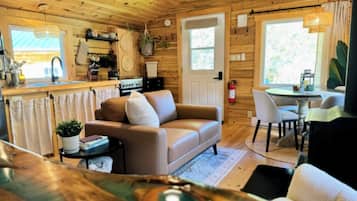 A cozy cabin interior with a sofa, dining table, and kitchen area.
