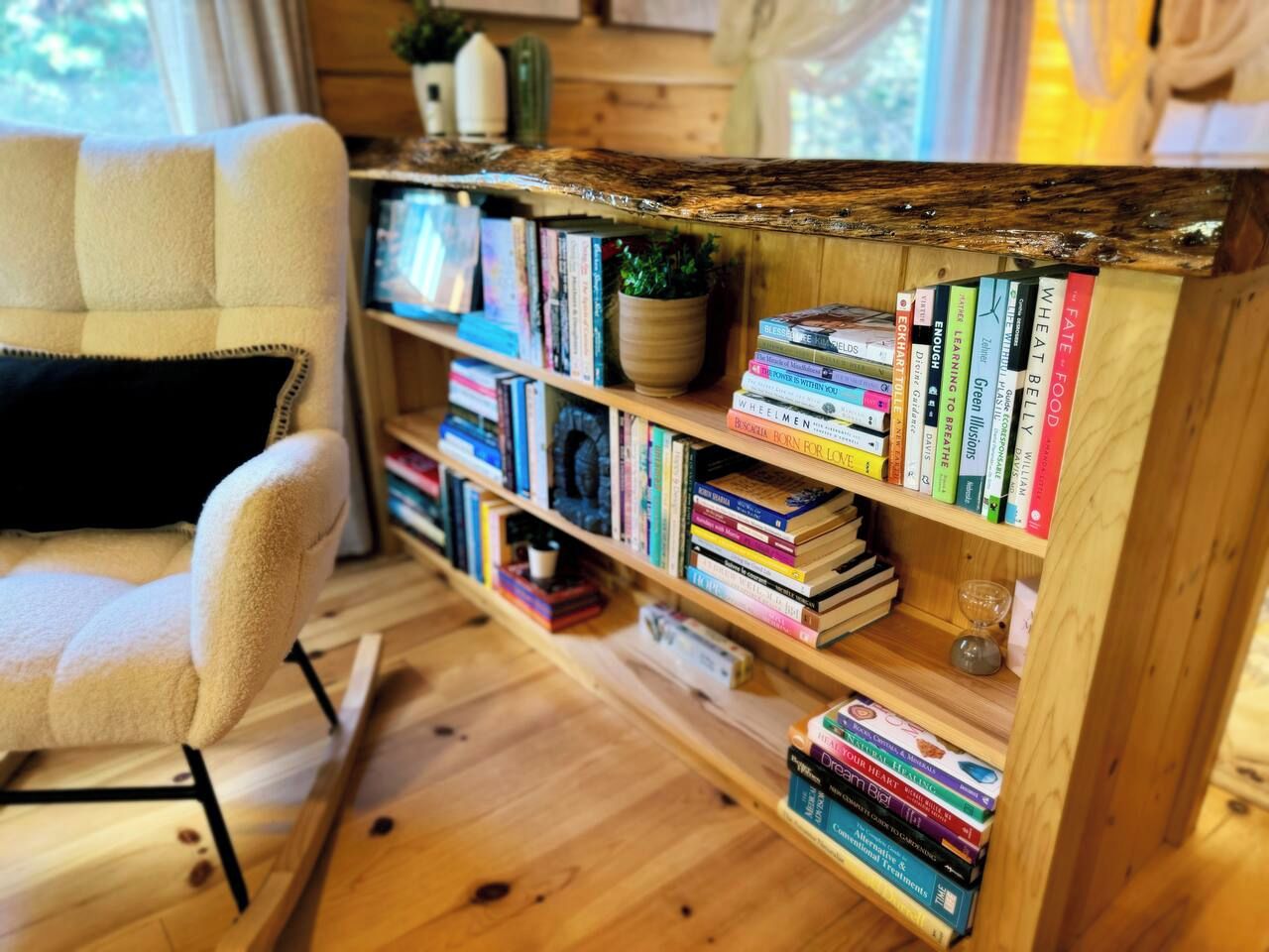 A cozy reading nook with a bookshelf filled with books, a comfortable chair, and a wooden floor.