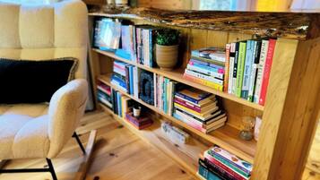 A cozy reading nook with a bookshelf filled with books, a comfortable chair, and a wooden floor.