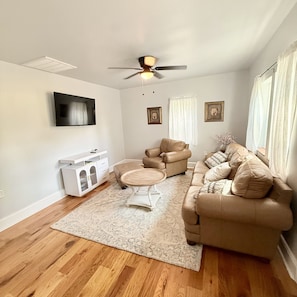 A living room with a beige sofa, a white coffee table, and a ceiling fan. - Cozy 2-bedroom cottage in Nottoway, VA (Crewe)