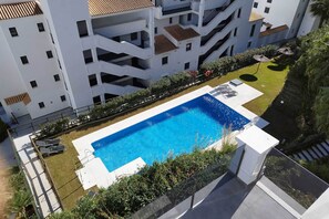 A residential building with a rooftop swimming pool, surrounded by greenery and a clear sky. - Sea View Apartment in Blue Suites (Manilva)