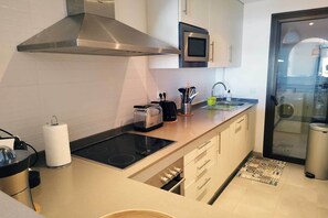 Eine moderne Küche mit einer Edelstahl-Dunstabzugshaube, einer Mikrowelle, einem Toaster und einem Spülbecken mit Armatur.