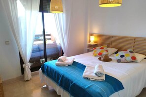 Ein Hotelzimmer mit Bett, Nachttisch, Lampe und Blick ins Freie.
