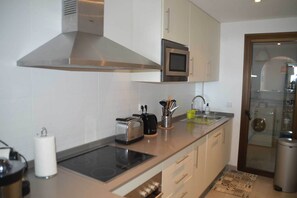 A modern kitchen with a stainless steel range hood, a microwave, and a built-in oven. - Apartment with Sea and Golf Course Views (Casares)