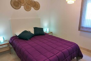 A room with a bed, two bedside tables, and a wall decoration. - Apartment with Sea and Golf Course Views (Casares)