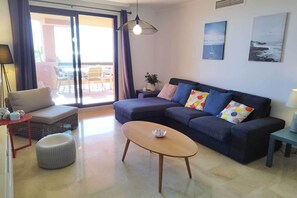 A living room with a sofa, a coffee table, a side table, and a lamp. - Apartment with Sea and Golf Course Views (Casares)