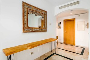 A hallway with a wooden bench, a decorative mirror, and a wooden door. - Apartment with private garden in Casares Playa (Casares)