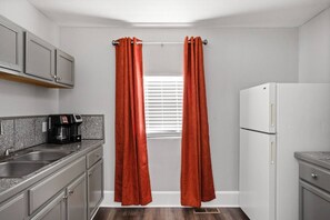 A compact kitchen with a coffee maker, a sink, and a refrigerator. - The Platypus - Spacious 1BR, Walk to Mass Ave (Indianapolis)