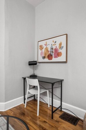 Een hoekzaak met een bureau, stoel en een lijst met een kunstwerk aan de muur.
