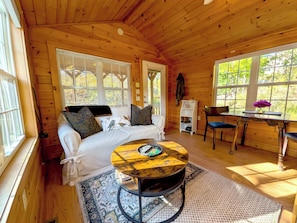 A cozy cabin interior with a bed, a round table, a chair, and a desk. - Kennebec River Cabin with Barrel Sauna & Porch (Richmond)