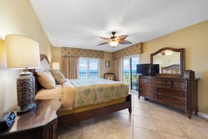 A hotel room with a bed, a dresser, a mirror, and a ceiling fan. - Reef Club 508 - Beachfront 3br/2ba luxury condo with pool and tennis (Indian Rocks Beach)