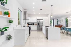 Une cuisine moderne avec des meubles blancs, des appareils en acier inoxydable et un îlot central.