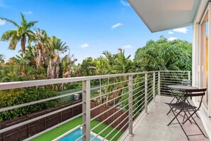 Un balcon avec une piscine, entouré d’une végétation luxuriante et de palmiers.