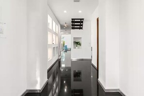 A modern hallway with white walls, a black floor, and recessed lighting. - Fort Lauderdale Beach 8BR Modern Retreat (Fort Lauderdale)