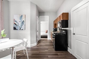 A modern kitchen with a black stove, wooden cabinets, and a white refrigerator. - The Manta Ray - Spacious Apt, Walk to Mass Ave (Indianapolis)