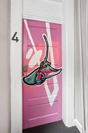 A pink door with a white number '4' and a graffiti design. - The Manta Ray - Spacious Apt, Walk to Mass Ave (Indianapolis)