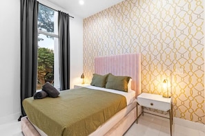 A bedroom with a bed, nightstands, a window with curtains, and patterned wallpaper. - Modern Luxe 2021Built Heated Pool/Jacuzzi/Gameroom (Fort Lauderdale)