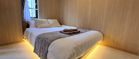 A modern bedroom with a bed, pillows, and a blanket.